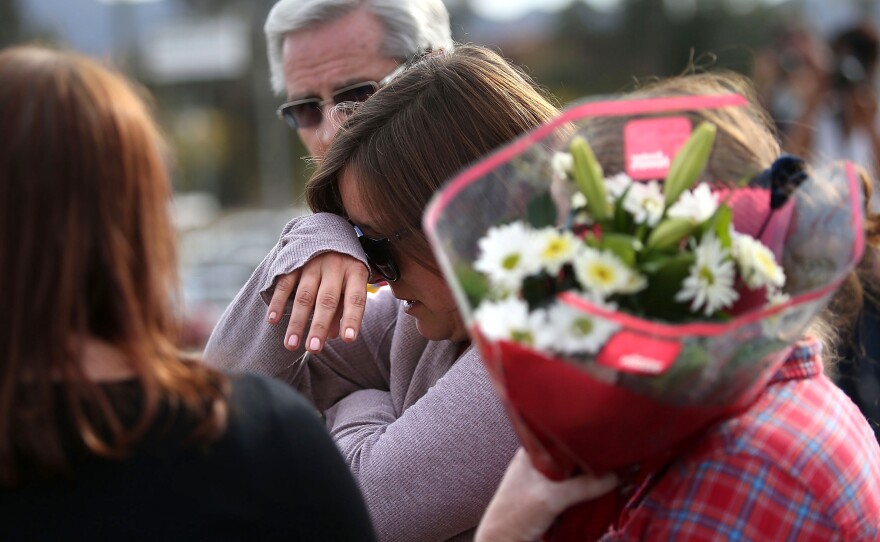 A mourner cries as she brings flowers to a roadblock outside the Inland Regional Center in San Bernardino, Calif., on Thursday.