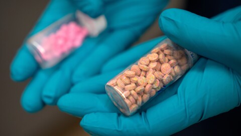 A forensic chemist with the Drug Enforcement Administration holds vials of fentanyl pills at a DEA research laboratory in this file photo. Fentanyl deaths are plunging in the U.S, but the recovery is threatened by a new "synthetic soup" of toxic street drugs.