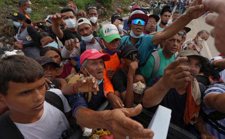 People reach out to receive supplies from volunteers on Tuesday, days after double earthquakes struck La Guaira, Venezuela.
