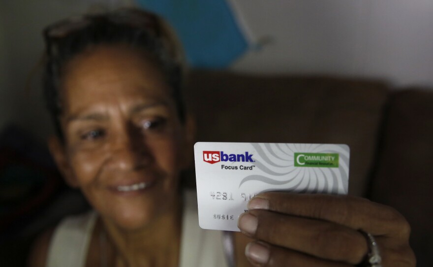 Stockton, Calif., resident Susie Garza displays the city-provided debit card she receives monthly as part of a pilot universal basic income program. The program began in 2019, when this photo was taken.