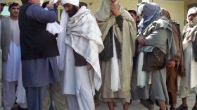 Kandahar Gov. Tooryalai Wesa, left, puts a turban on former Taliban fighter Malawi Azizullah.