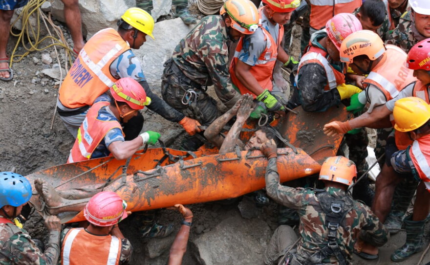 In this photo provided by the Nepal Army, soldiers rescue a worker alive from a tunnel during an ongoing operation at the Trishuli-3A hydropower project in Nepal's Rasuwa district, Friday.