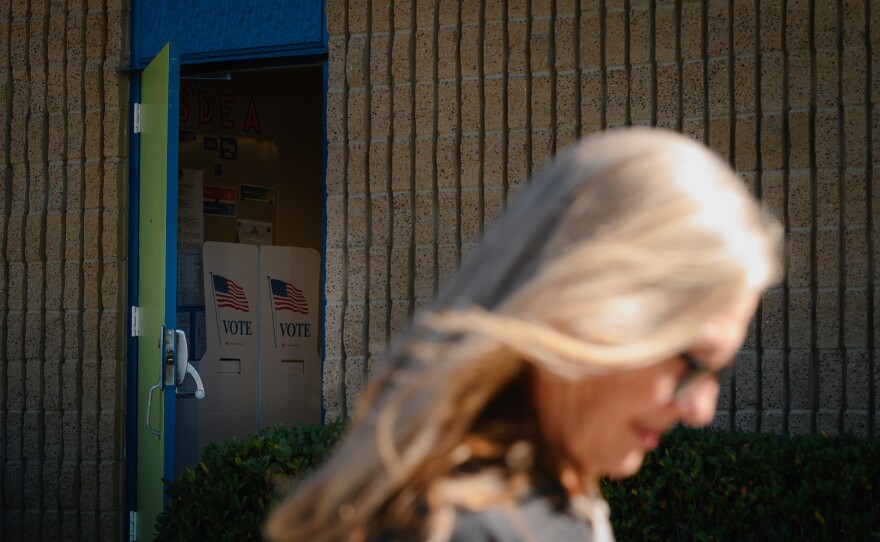A woman passes by a propped door showing voting booths on Nov. 5, 2024.