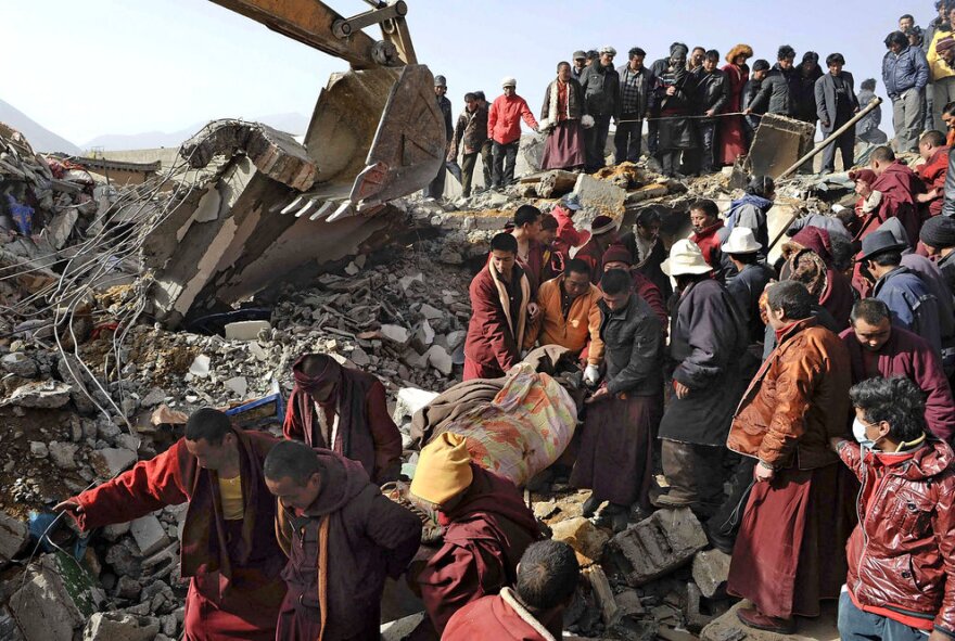 Rescue crews, including Buddhist monks, carry a blanket-wrapped earthquake victim pulled from the rubble Thursday after a magnitude 6.9 temblor hit Yushu county in China's Qinghai province. Rescue workers and equipment began streaming into the mountainous region a day after a series of quakes killed more than 600 people and injured thousands.