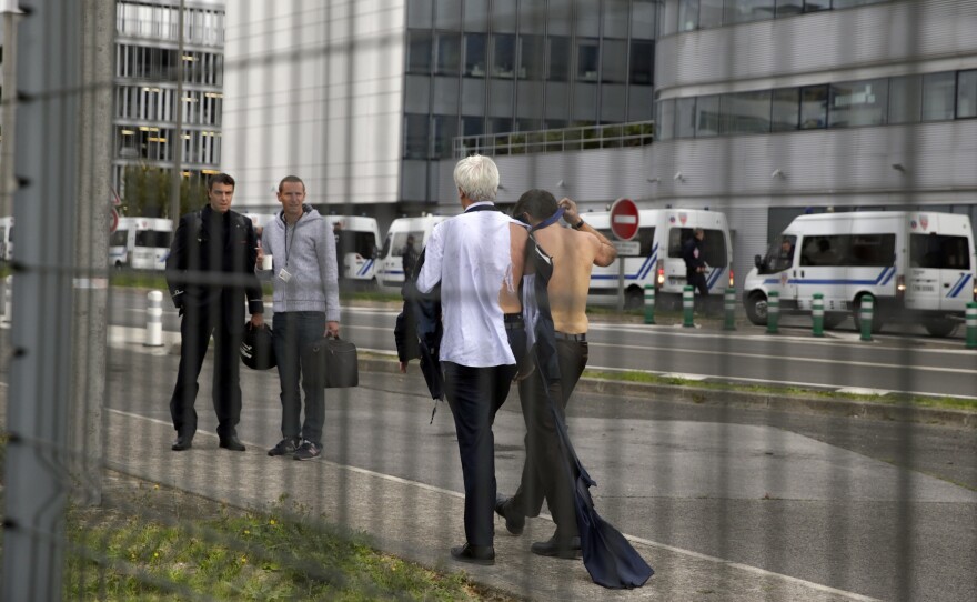 Air France executives Xavier Broseta (shirtless) and Pierre Plissonnier walk away from demonstrators.