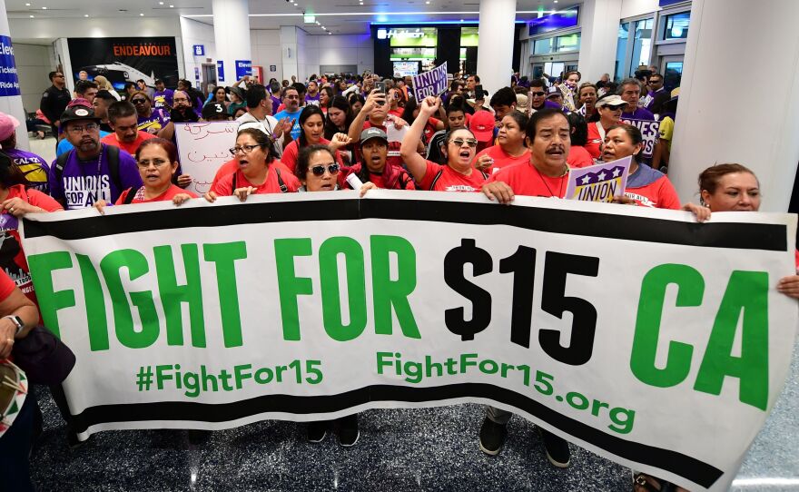 Airport employees, Uber and Lyft drivers, and other workers protest for a $15 minimum wage at Los Angeles International Airport in October. Increases in minimum wages contributed to bigger pay gains for lower-income workers.