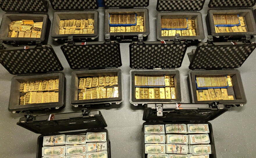 This image provided by U.S. Department of Justice, and contained in a court filing, shows gold bars and cash that was seized from a David J. Rush's home, during a search on May 19, 2026, in Ashburn, Va.