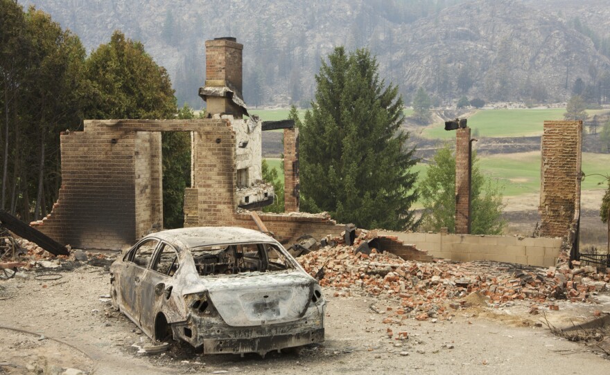 A burned-out car sits in front of a ruined house in this photo taken Sunday near Pateros, Wash. Large fires have destroyed hundreds of homes in the state this month.