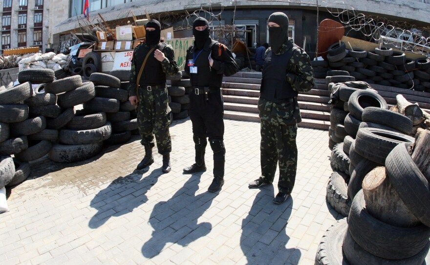 Masked pro-Russian activists guard a barricade outside the regional state building seized by separatists in the eastern Ukrainian city of Donetsk Saturday. Pro-Russian forces holding a group of international observers have accused them of being "NATO spies."