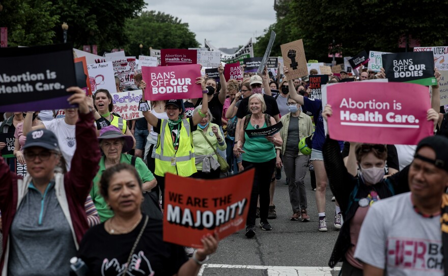 Pro-abortion rights demonstrators march in Washington, D.C., on May 14. While most U.S. adults favor some restrictions on abortion, according to our new poll, most also say they do not support overturning <em>Roe v. Wade</em>.