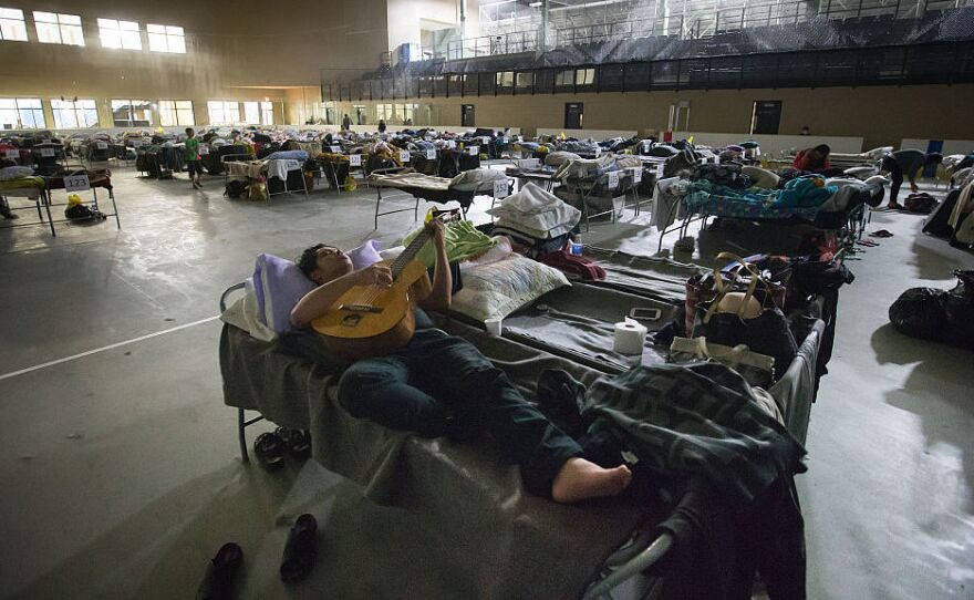 A Fort McMurray evacuee plays a guitar while lying on a cot at a hockey rink in Lac La Biche, Alberta, Canada, on Saturday.