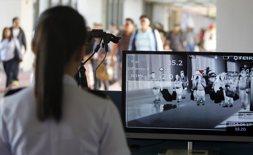 Airline passengers traveling from the United Arab Emirates pass through a scanner designed to detect people with a fever in Manila, the Philippines, in April.