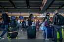 Travelers, some wearing masks, wait in long lines to check luggage before going through airport security on their way out of San Diego, Calif. Dec. 23, 2022.