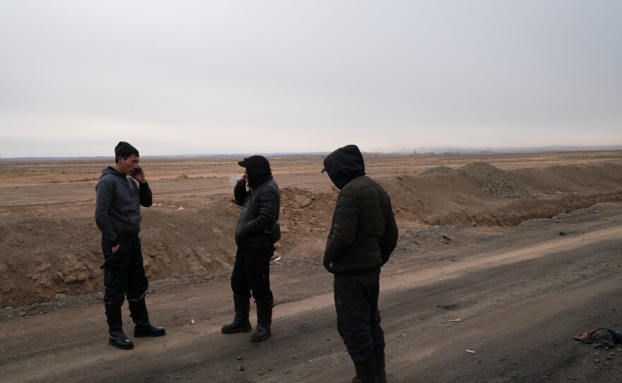 Drivers take a cigarette break while waiting for the line of coal trucks to budge. Many share traffic information over social media apps.