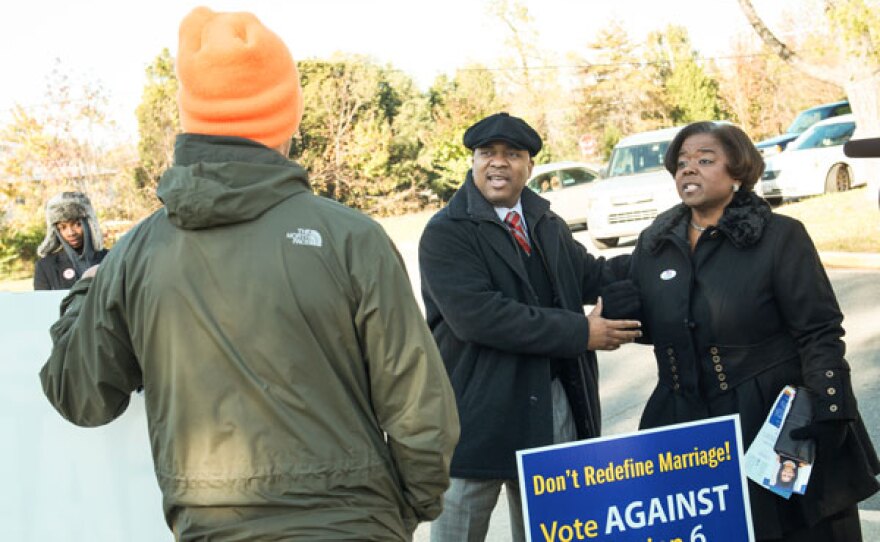 Sharon and Alvin talking to a volunteer. Sharon and Alvin have a sign that reads "Don't Redefine Marriage! Vote against Question 6."