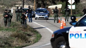 Police search cars at a blockade as they come down the mountain during a manhunt for the former Los Angeles Police Department officer who is suspected of triple murder on February 12, 2013 in Yucaipa, California.
