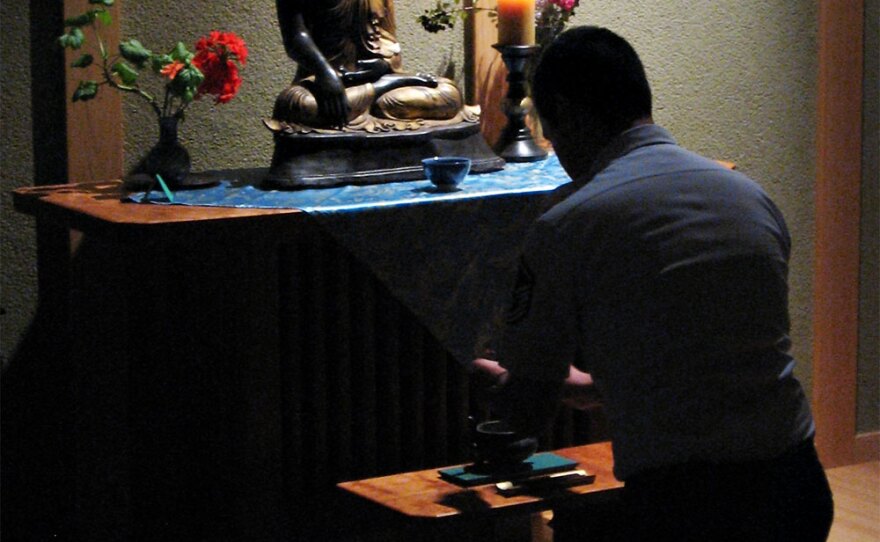 Steve Honda, an Air Force Academy military trainer, kneels before the altar in the base's Buddhist chapel.