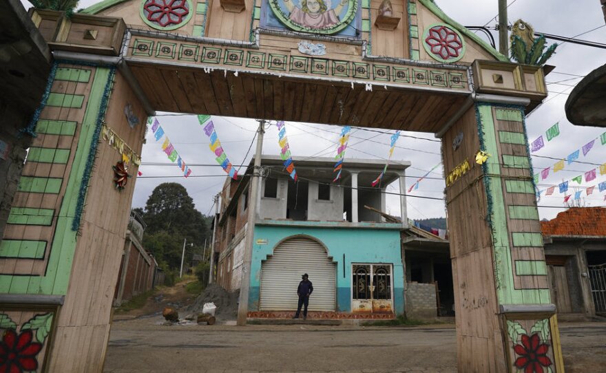 A community police officer stands guard at the main gate to the Purepecha Indigenous community of Comachuen, Michoacan state, Mexico, Wednesday, Jan. 19, 2022.