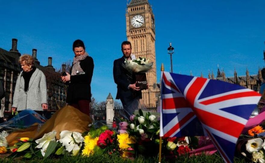 People lay floral tributes to the victims of the March 22 terror attack in Parliament Square outside the Houses of Parliament in central London.