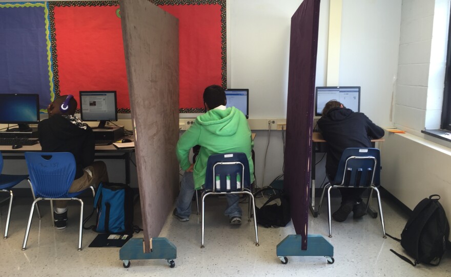Students in the Aspire program work individually at computers separated by privacy screens. The partitions help the students feel less anxious.