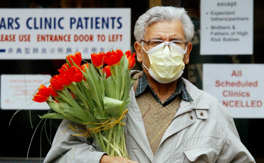 A man wears a protective mask as he carries a bouquet of flowers at Women's College Hospital in Toronto in March 2003, when SARS fears about were widespread.