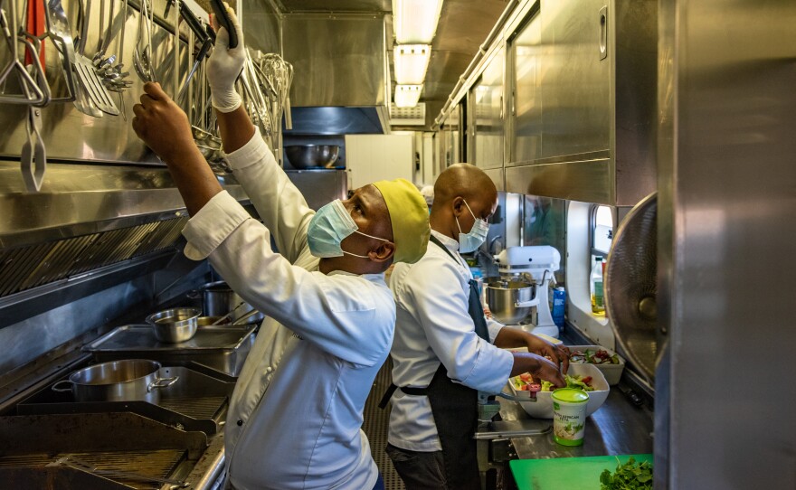 Chef Nangamso Gwiliza reaches for a utensil in the kitchen of the Phelophepa in Thaba Nchu, South Africa. Operating out of a tiny space in carriage No. 5, Gwiliza and his team cook over 100,000 meals per year for the train's staff and contractors.