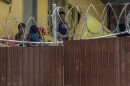Migrant children look out over a barb wire fence at the Ágape Misíon Mundial shelter in Tijuana, Mexico, April 25, 2023.