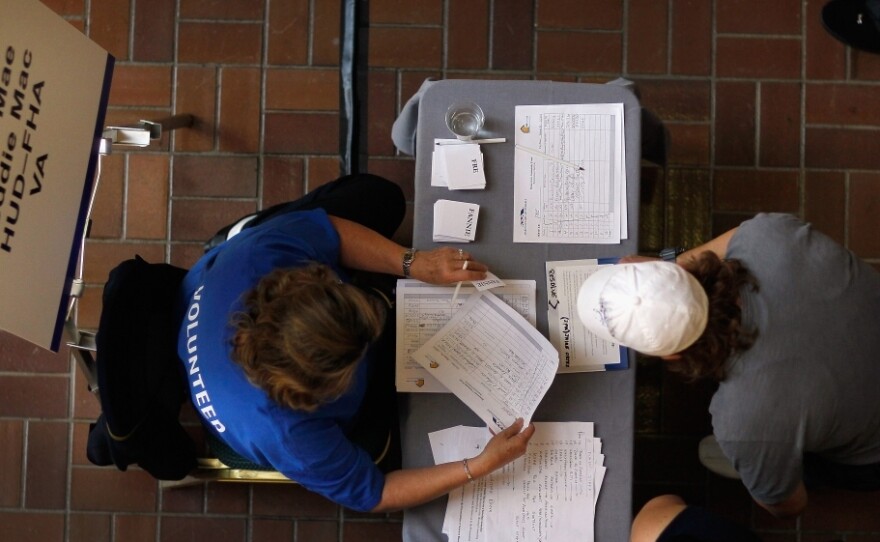 A Fannie Mae/Freddie Mac mortgage services representative (left) helps a person register for mortgage help in Miami.