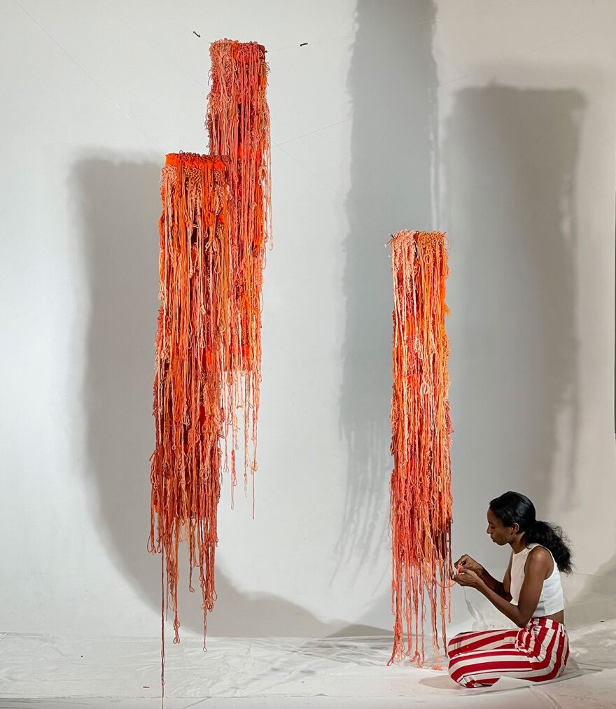Artist Denja Harris is shown finishing up her fiber art installation at Intervals gallery in an undated photo.