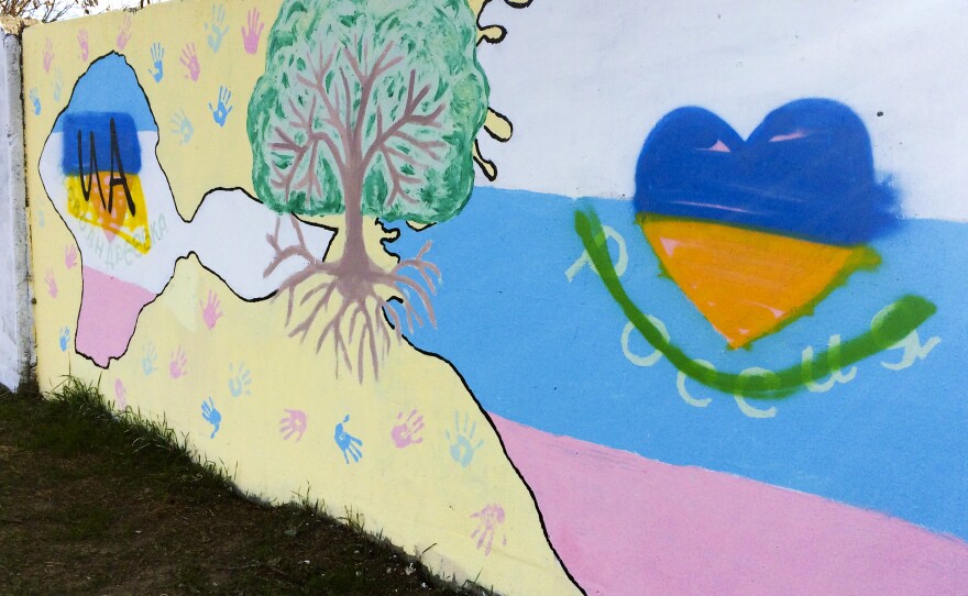 Most of the artwork on this wall near Crimea's main airport is pro-Russian. But the blue-and-yellow heart is painted in the colors of Ukraine's flag, and the green line covers the word "Russia."