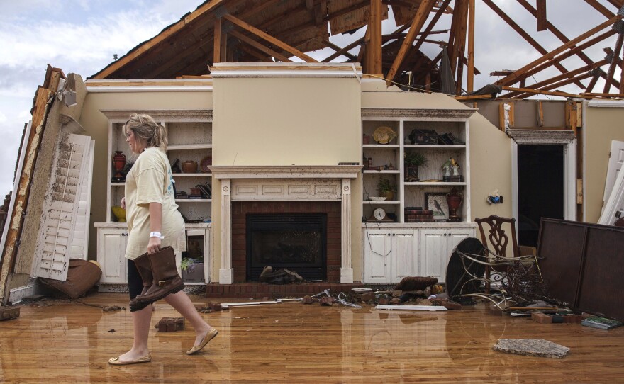 Jenny Bullard carries a pair of boots from her home that was damaged by a tornado in Adel, Ga.