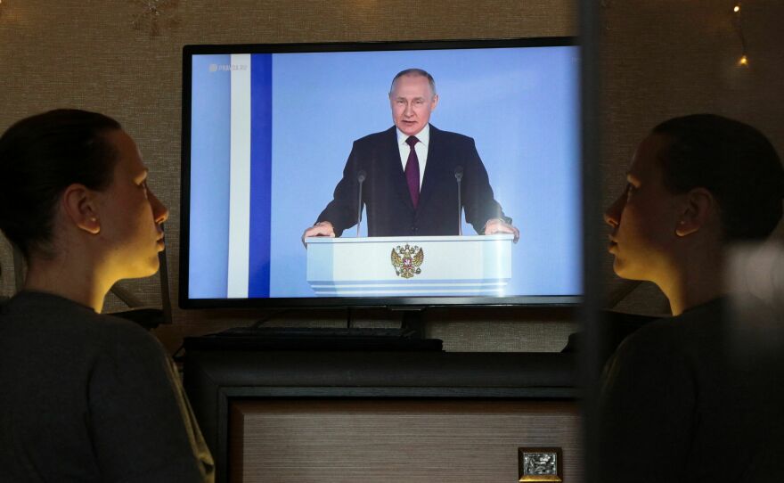 A woman in Simferopol, Crimea, watches a TV broadcast of Russian President Vladimir Putin's annual state of the nation address on Tuesday. Putin announced Russia is suspending participation in the New START nuclear weapons treaty.