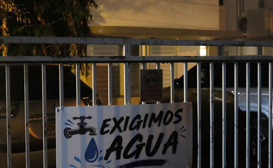 A sign demanding water is affixed to the gates outside the condo building — one building among many across Puerto Rico to which the island's public utility has cut running water.