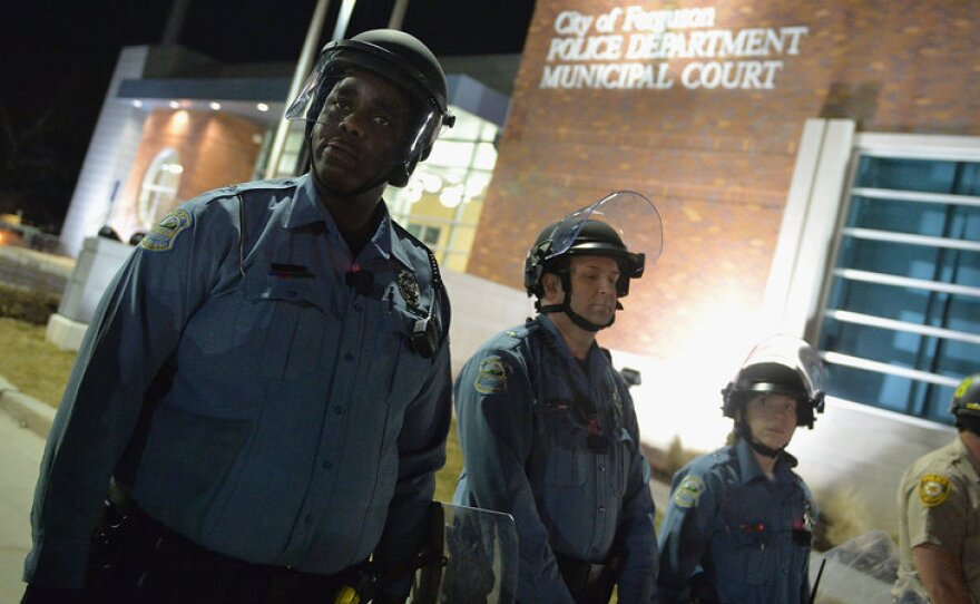 Police in riot gear respond to demonstrators blocking traffic during a protest outside the Ferguson Police Department in Missouri Wednesday. As the protests were ending, someone fired at the police — wounding two officers.