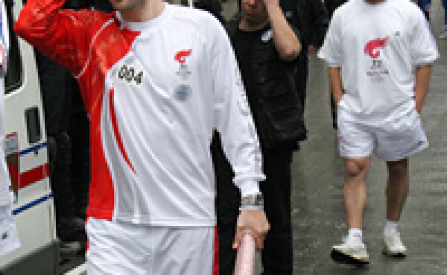French former tennis player (center) Arnaud Di Pasquale reacts as he carries an extinguished Beijing Olympics flame in Paris on his way to place the torch in a bus for safety amid pro-Tibet protests.