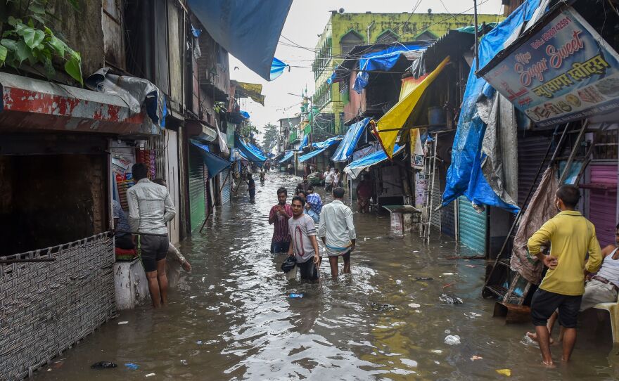 Residents wade in a flooded street after heavy monsoon rains in Mumbai on August 4, 2019.