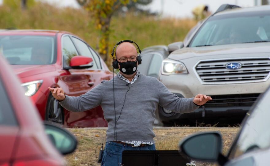 Shantz conducts Luminous Voices' first car concert, on Oct. 4, 2020. Audience vehicles are seen parked to behind him.