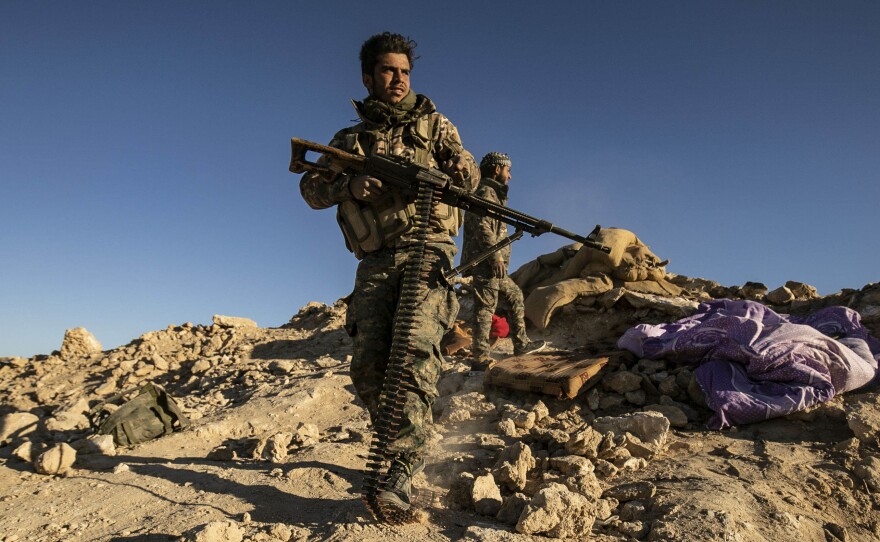 Fighters with the U.S.-backed Syrian Democratic Forces hold a position on a hilltop overlooking the last ISIS enclave in the village of Baghouz.