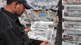 A man at a newsstand in Karachi, Pakistan, reads an Urdu-language evening newspaper reporting the capture of a top Taliban commander.
