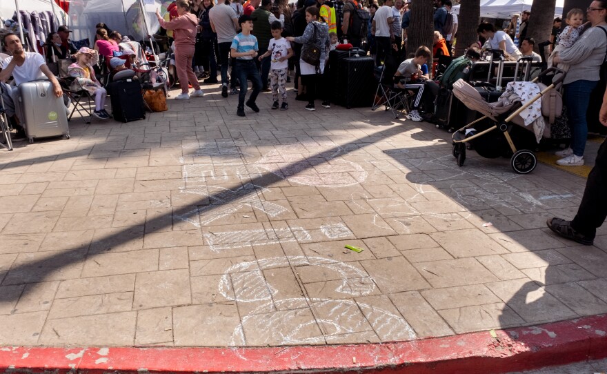 Ukrainian war refugee children draw the word "Mexico" with a heart over it at the make-shift camp they are waiting at in Tijuana for the chance to claim asylum in the United States, April 1, 2022.