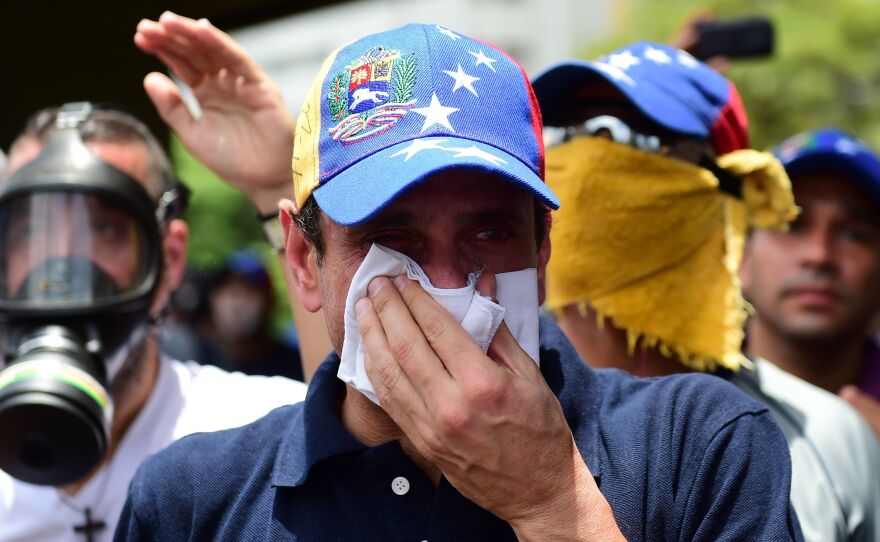 Opposition leader Henrique Capriles, who was banned from public office for 15 years, protects himself against tear gas during a rally against Maduro on Wednesday.