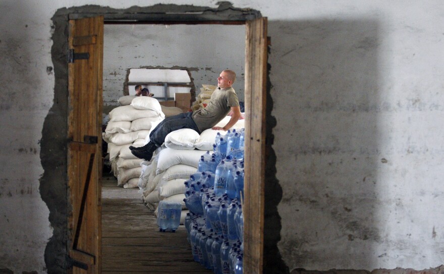 An aid worker takes a break on a big pile of food, which was brought to the small eastern Ukrainian city of Starobilsk by a humanitarian convoy.