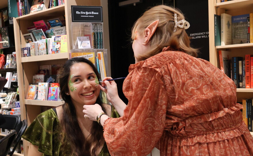 Dalia Luque, left, has her face painted by Amber Lovold, one of the organizers of a midnight release party at Politics and Prose in Washington, D.C. They are celebrating the publication of A Court of Splintered Harmony, the latest installment of Sarah J. Maas' popular romantasy series.