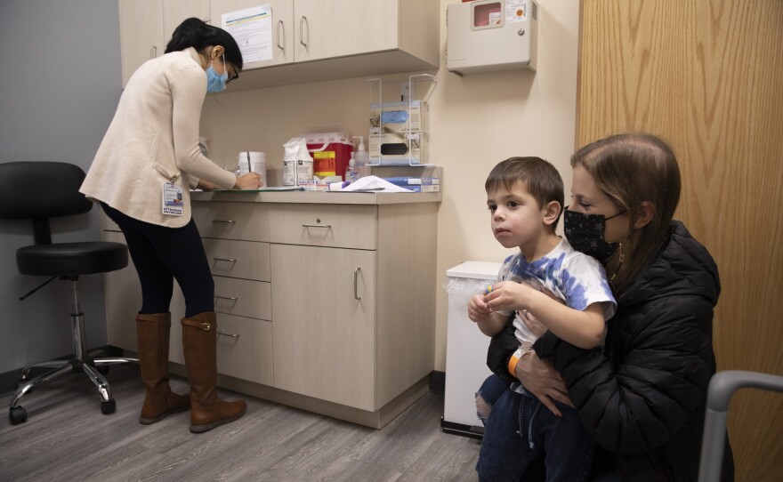FILE - Ilana Diener holds her son, Hudson, 3, during an appointment for a Moderna COVID-19 vaccine trial in Commack, N.Y. on Nov. 30, 2021. On Thursday, April 28, 2022, Moderna asked U.S. regulators to authorize low doses of its COVID-19 vaccine for children younger than 6, a long-awaited move toward potentially opening shots for millions of tots by summer.