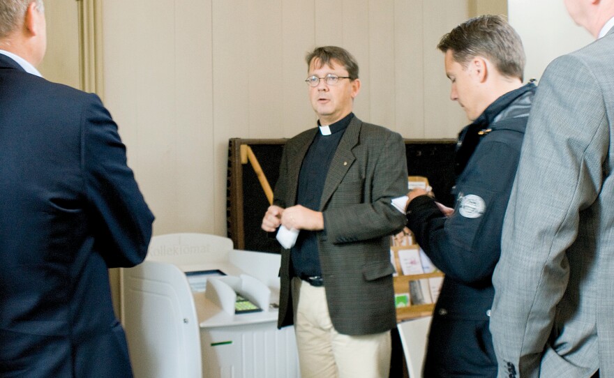 In this photo from 2011, Vicar Johan Tyrberg of the Carl Gustaf Church in Karlshamn, southern Sweden, stands next to a credit card machine enabling worshippers to donate money to the church collection electronically.