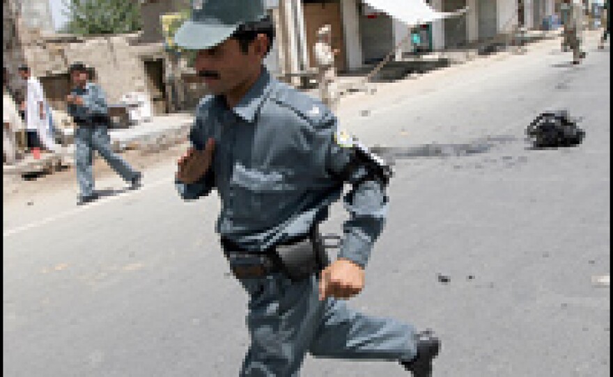 A member of the Afghan National Police runs away from the wreckage of the U.S. armored vehicle.