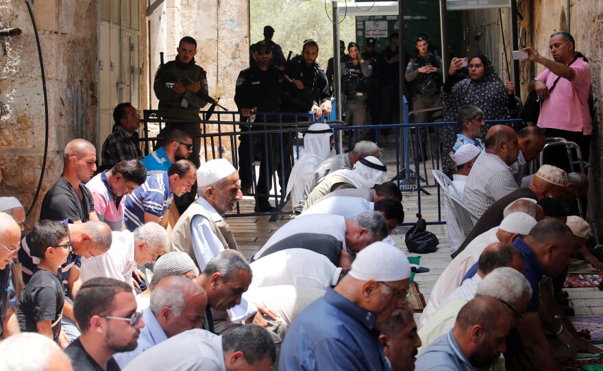 Palestinians pray near new metal detectors that were erected outside one of the main entrances to Al-Aqsa mosque in Jerusalem on Thursday. Increased security measures at the site have touched off protests.