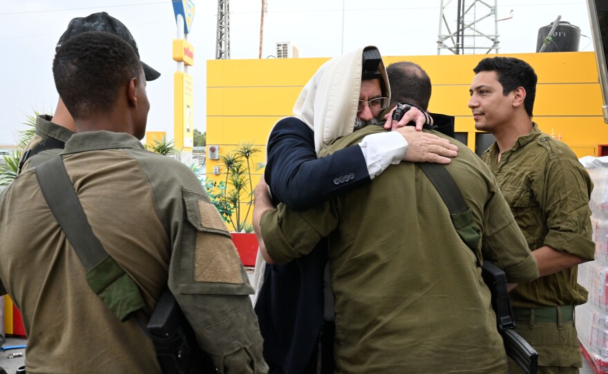 One by one, a religious Jewish man gives soldiers a long hug.