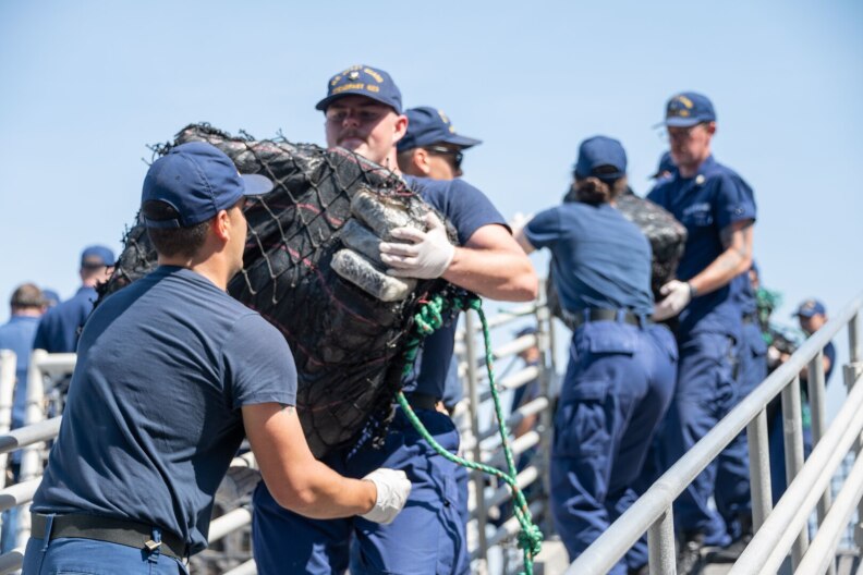 Crew members from the U.S. Coast Guard Cutter Steadfast (WMEC 623) stack interdicted, illegal drugs on the flight deck of the cutter as they prepare to offload in San Diego, July 17, 2023.