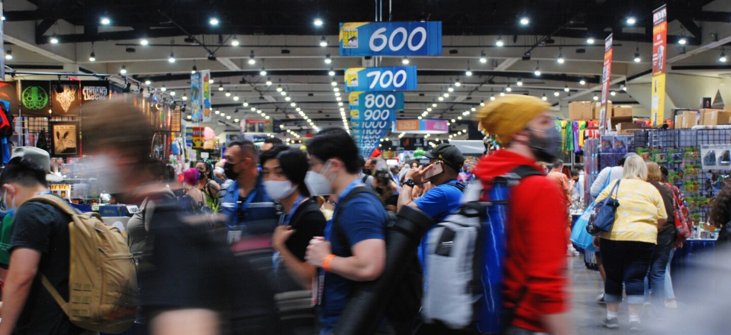 Hundreds of mask-wearing attendees throng the floor at Comic-Con 2022